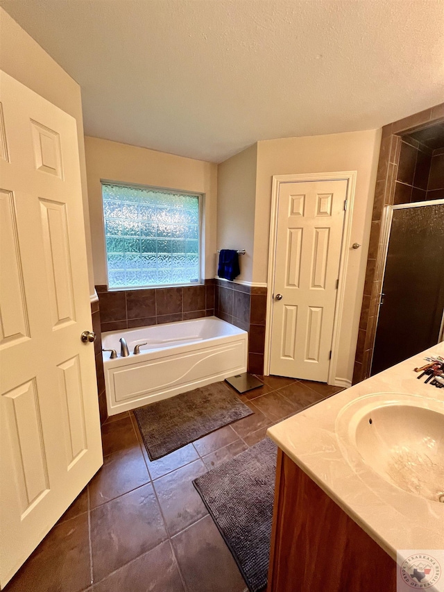 bathroom with plus walk in shower, a textured ceiling, tile patterned flooring, and vanity