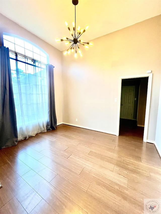 unfurnished room with light wood-type flooring and a notable chandelier