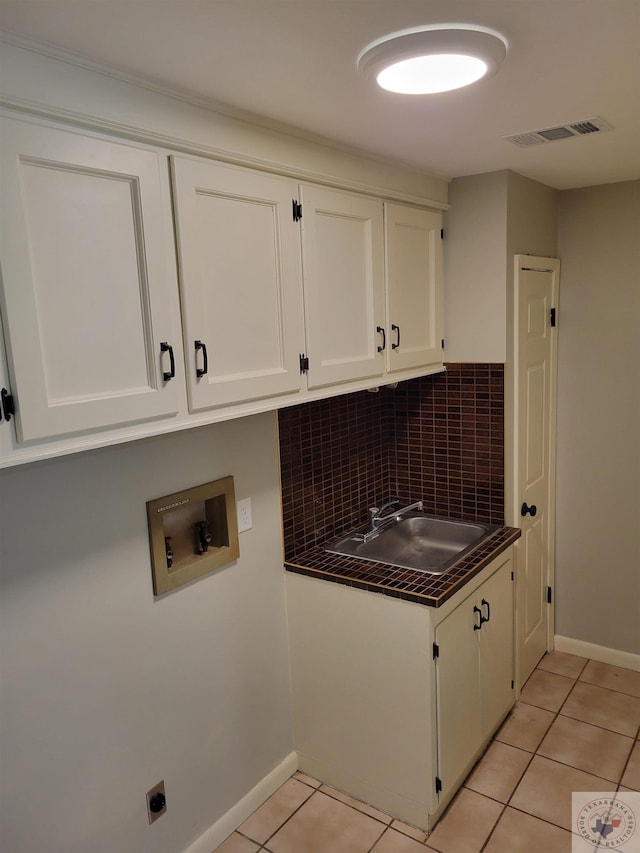 clothes washing area featuring cabinets, washer hookup, sink, hookup for an electric dryer, and light tile patterned floors