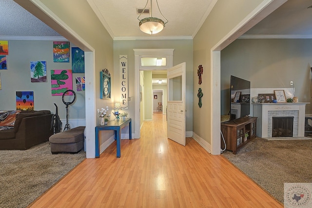 corridor featuring hardwood / wood-style floors, ornamental molding, and a textured ceiling