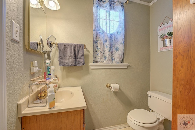 bathroom with toilet, vanity, and ornamental molding