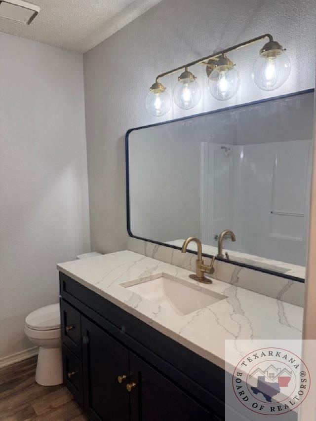 bathroom with wood-type flooring, a textured ceiling, toilet, and vanity