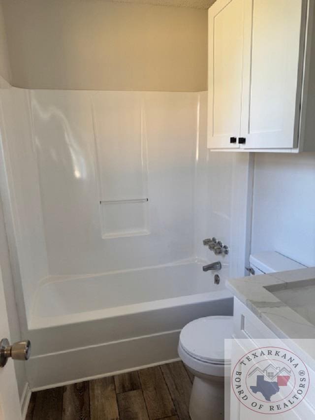 bathroom with hardwood / wood-style floors, toilet, and shower / washtub combination