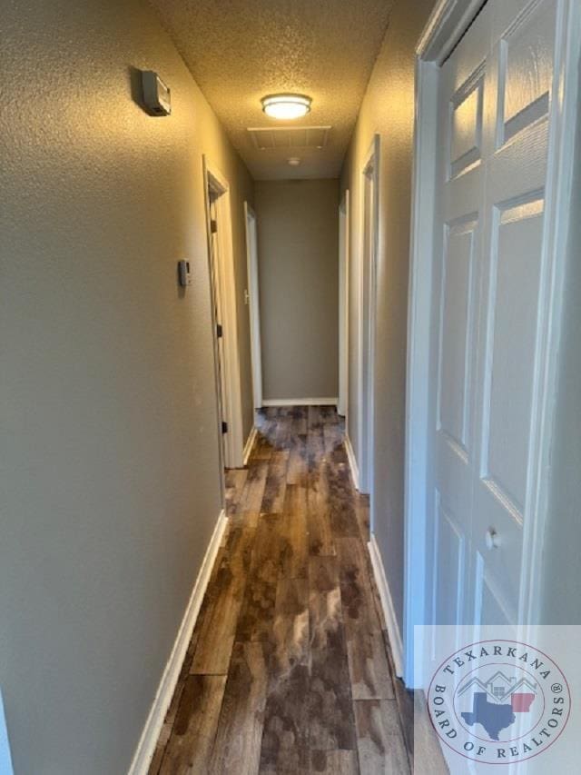 hall with dark wood-type flooring and a textured ceiling