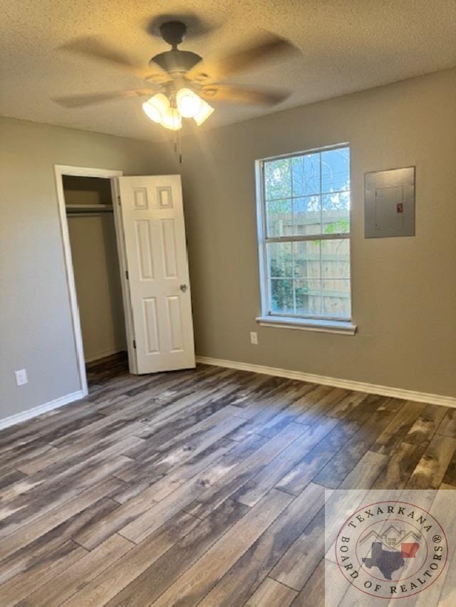 unfurnished bedroom featuring hardwood / wood-style floors, a textured ceiling, a closet, ceiling fan, and electric panel