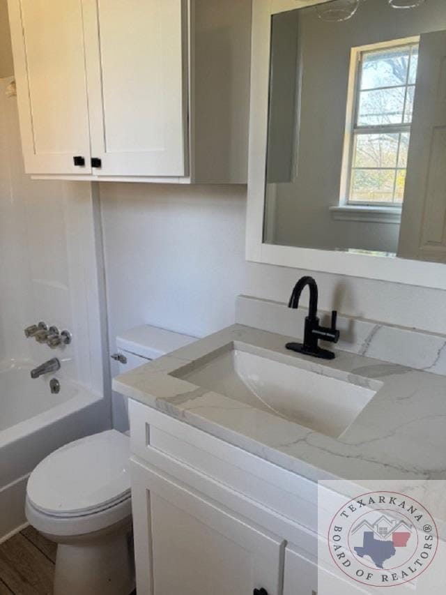 full bathroom featuring vanity, washtub / shower combination, hardwood / wood-style floors, and toilet