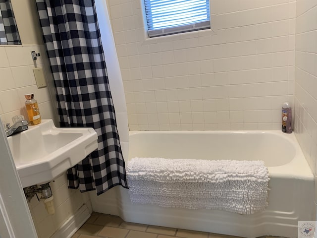 bathroom with decorative backsplash, sink, tile walls, and shower / bath combo with shower curtain