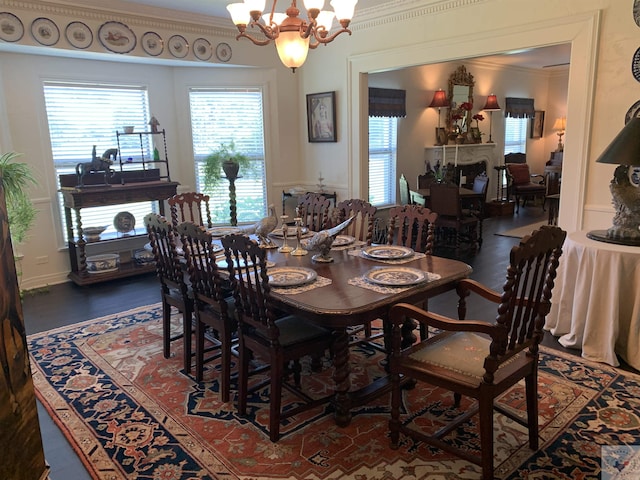 dining area with a notable chandelier, ornamental molding, and dark hardwood / wood-style flooring