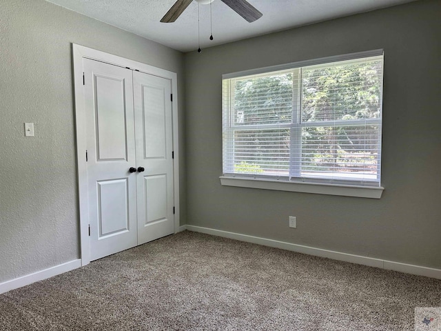 unfurnished bedroom featuring a closet, ceiling fan, carpet flooring, and multiple windows