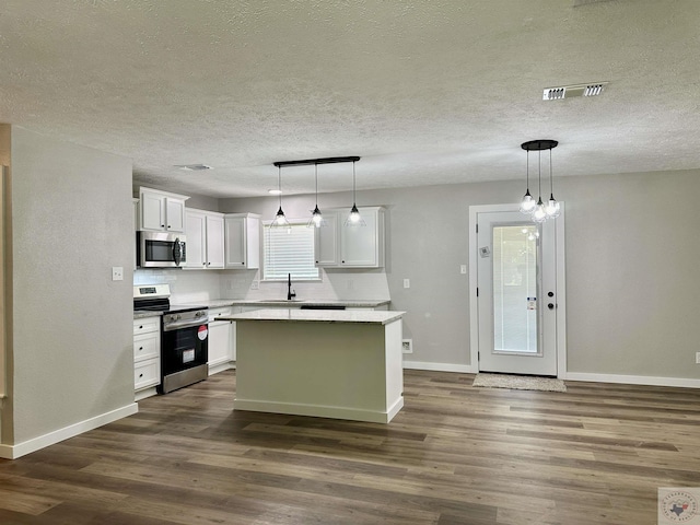 kitchen with pendant lighting, appliances with stainless steel finishes, backsplash, white cabinetry, and a center island