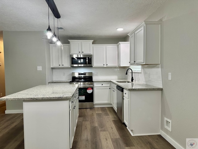 kitchen featuring stainless steel appliances, white cabinetry, light stone counters, and pendant lighting