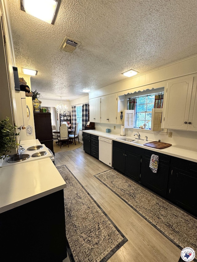 1509 W 40th St, Texarkana, TX 75503 - kitchen featuring dark cabinets, dishwasher, light wood-type flooring, light countertops, and white cabinetry