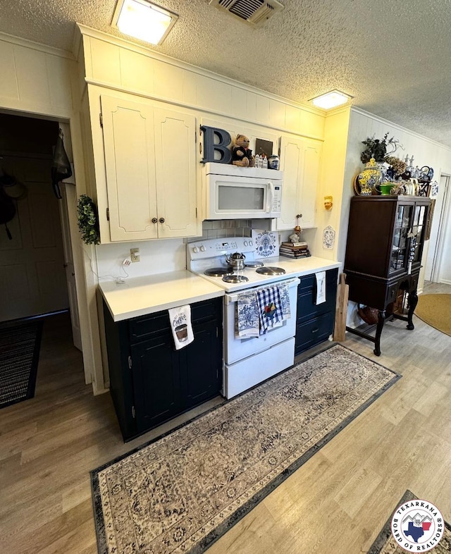 1509 W 40th St, Texarkana, TX 75503 - kitchen featuring white appliances, crown molding, light wood-style flooring, a textured ceiling, and light countertops