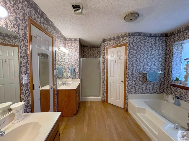 bathroom with independent shower and bath, vanity, a textured ceiling, and wood-type flooring