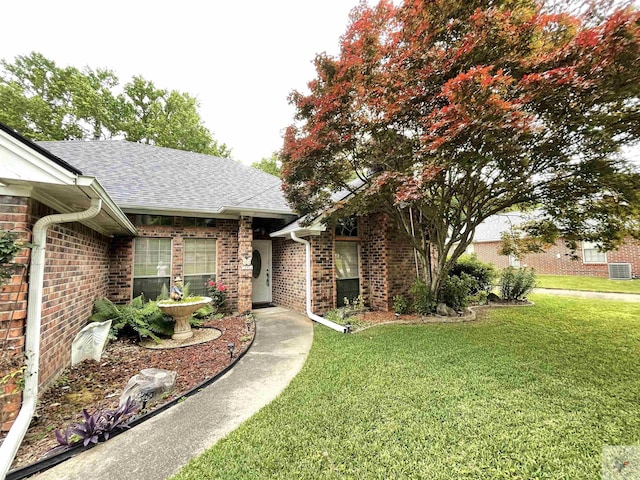 130 Westline Rd, Wake Village, TX 75501 - view of front of home with a front lawn, central AC, roof with shingles, and brick siding