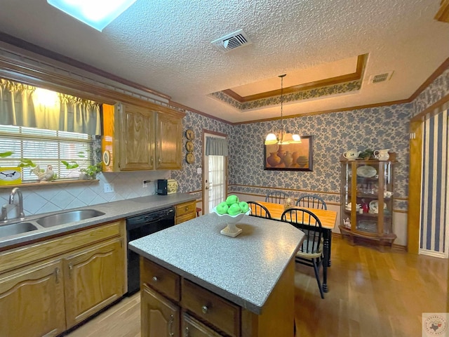 kitchen featuring a center island, black dishwasher, sink, hanging light fixtures, and a raised ceiling