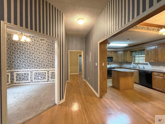 130 Westline Rd, Wake Village, TX 75501 - kitchen featuring wallpapered walls, black appliances, a kitchen island, a textured ceiling, and light wood-style flooring
