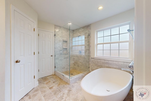 bathroom featuring tile walls and independent shower and bath