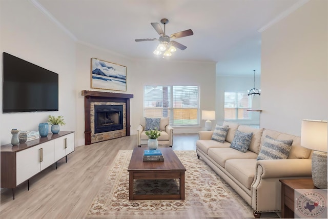 living room featuring crown molding, light wood-type flooring, and ceiling fan with notable chandelier