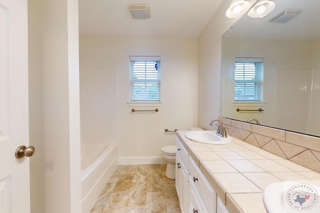 bathroom featuring vanity, toilet, plenty of natural light, and a washtub