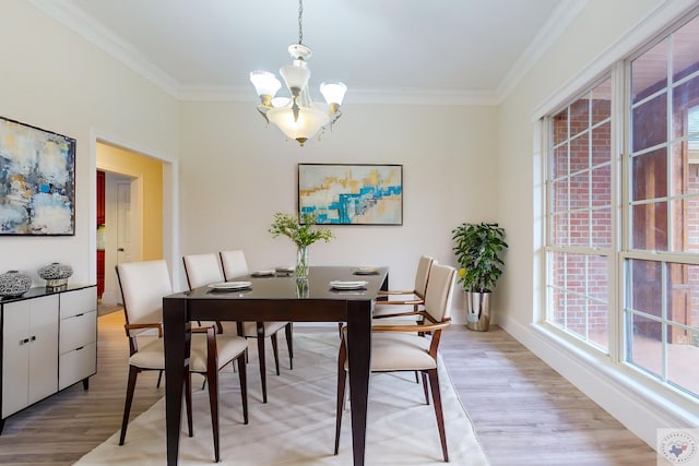 dining room featuring crown molding, an inviting chandelier, light hardwood / wood-style flooring, and plenty of natural light