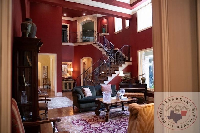 living room featuring crown molding, hardwood / wood-style floors, and a high ceiling