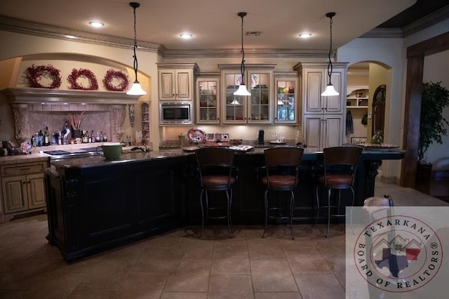 bar featuring stainless steel microwave, pendant lighting, and tile patterned flooring