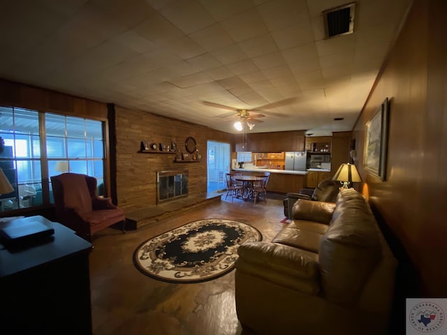 living room with a fireplace, wood walls, and ceiling fan