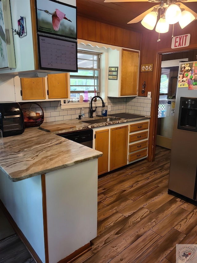 kitchen featuring black dishwasher, sink, kitchen peninsula, dark hardwood / wood-style flooring, and stainless steel fridge