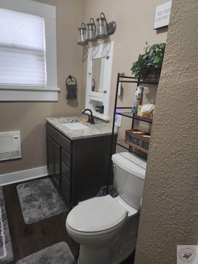 bathroom with hardwood / wood-style flooring, vanity, heating unit, and toilet