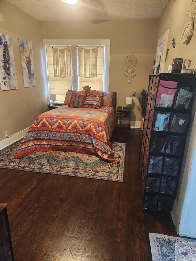 bedroom with dark hardwood / wood-style floors and a textured ceiling