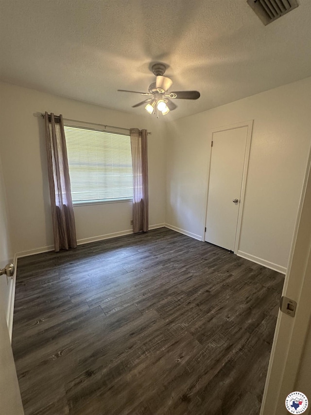 29 E Greenfield Dr, Wake Village, TX 75501 - unfurnished bedroom featuring a textured ceiling, dark wood finished floors, ceiling fan, and baseboards