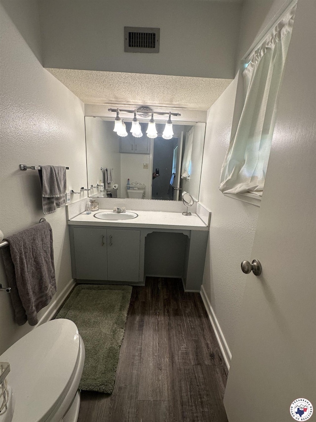 29 E Greenfield Dr, Wake Village, TX 75501 - bathroom with wood finished floors, toilet, baseboards, vanity, and a textured ceiling