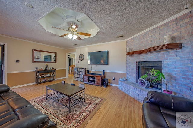 living room featuring crown molding, a textured ceiling, a fireplace, and light hardwood / wood-style flooring