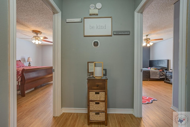 hall with light hardwood / wood-style floors and a textured ceiling