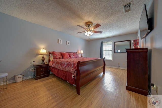 bedroom featuring ceiling fan, light hardwood / wood-style floors, and a textured ceiling