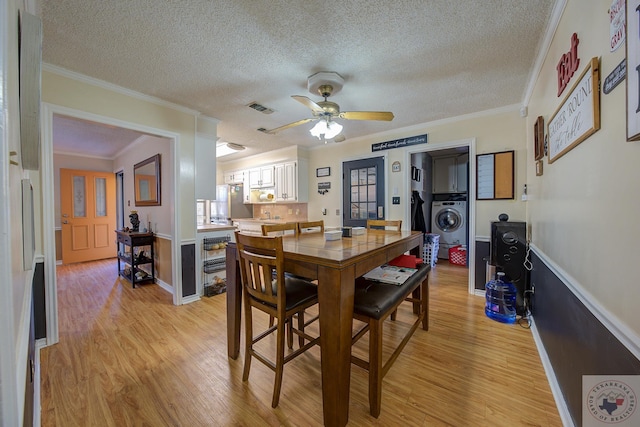 dining space with washer / clothes dryer, ornamental molding, a textured ceiling, and light hardwood / wood-style floors