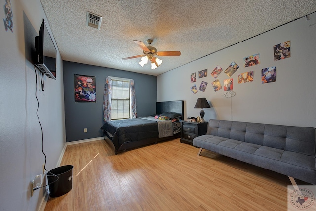 bedroom featuring ceiling fan, hardwood / wood-style floors, and a textured ceiling