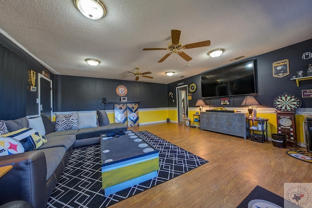 living room with ceiling fan, wood-type flooring, and a textured ceiling