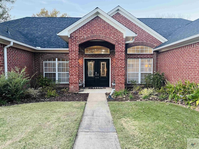 view of exterior entry featuring a yard and french doors