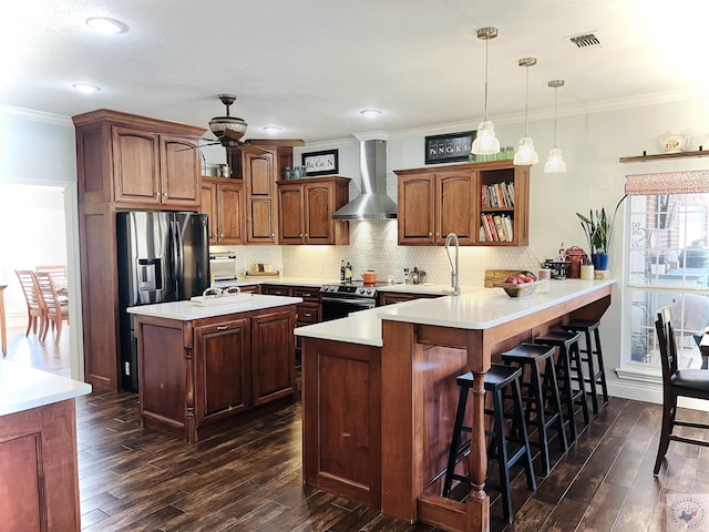 kitchen featuring wall chimney exhaust hood, stainless steel appliances, a kitchen breakfast bar, kitchen peninsula, and crown molding