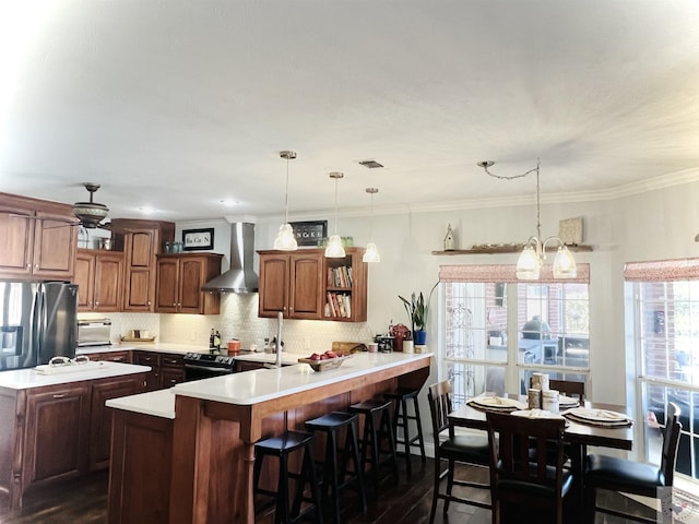 kitchen with kitchen peninsula, pendant lighting, a breakfast bar area, and wall chimney range hood