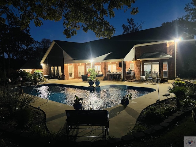 pool at twilight featuring a patio