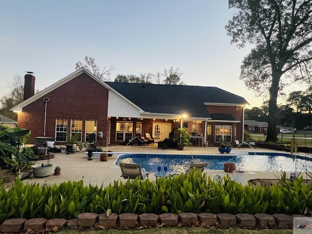 back house at dusk featuring a patio area and pool water feature