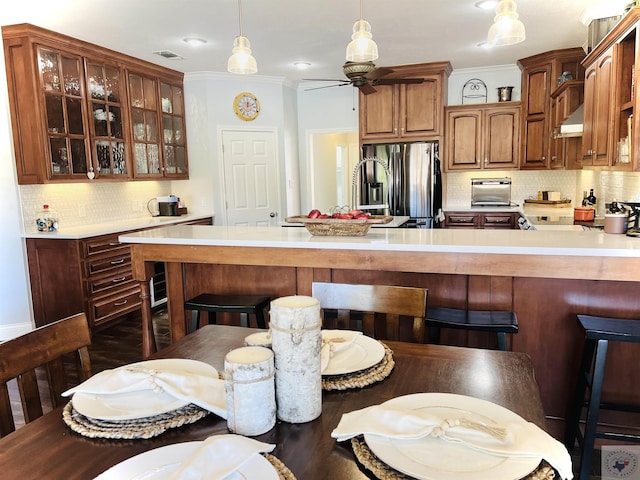 kitchen with ceiling fan, decorative backsplash, stainless steel fridge with ice dispenser, and hanging light fixtures