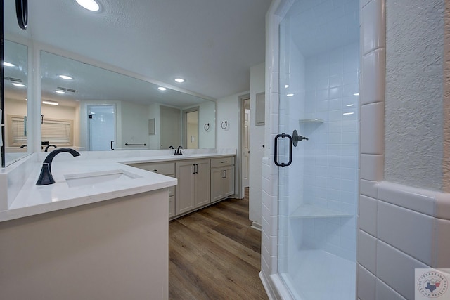 bathroom featuring wood-type flooring, a shower with door, and vanity