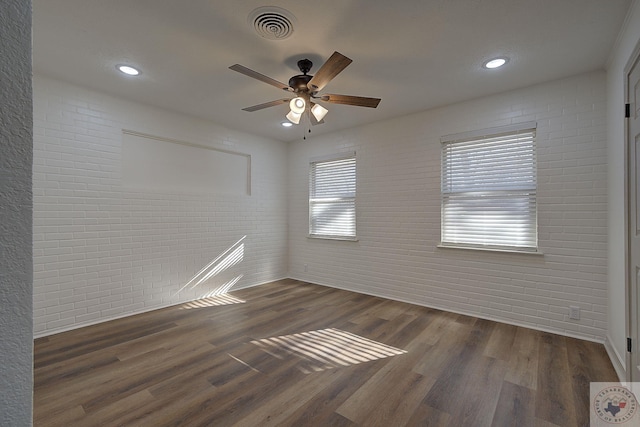 spare room featuring ceiling fan, brick wall, and dark hardwood / wood-style flooring