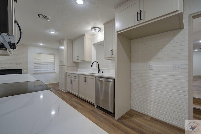 kitchen with dark wood-type flooring, sink, appliances with stainless steel finishes, light stone countertops, and white cabinets