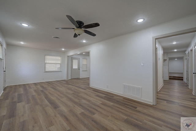 empty room featuring ceiling fan, brick wall, dark hardwood / wood-style flooring, and a textured ceiling