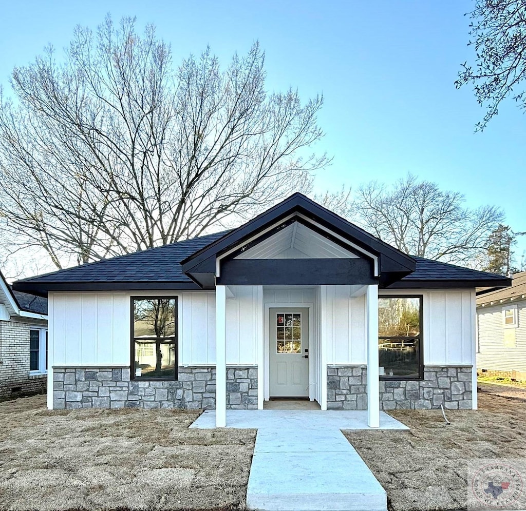 view of front of home featuring stone siding, board and batten siding, and roof with shingles